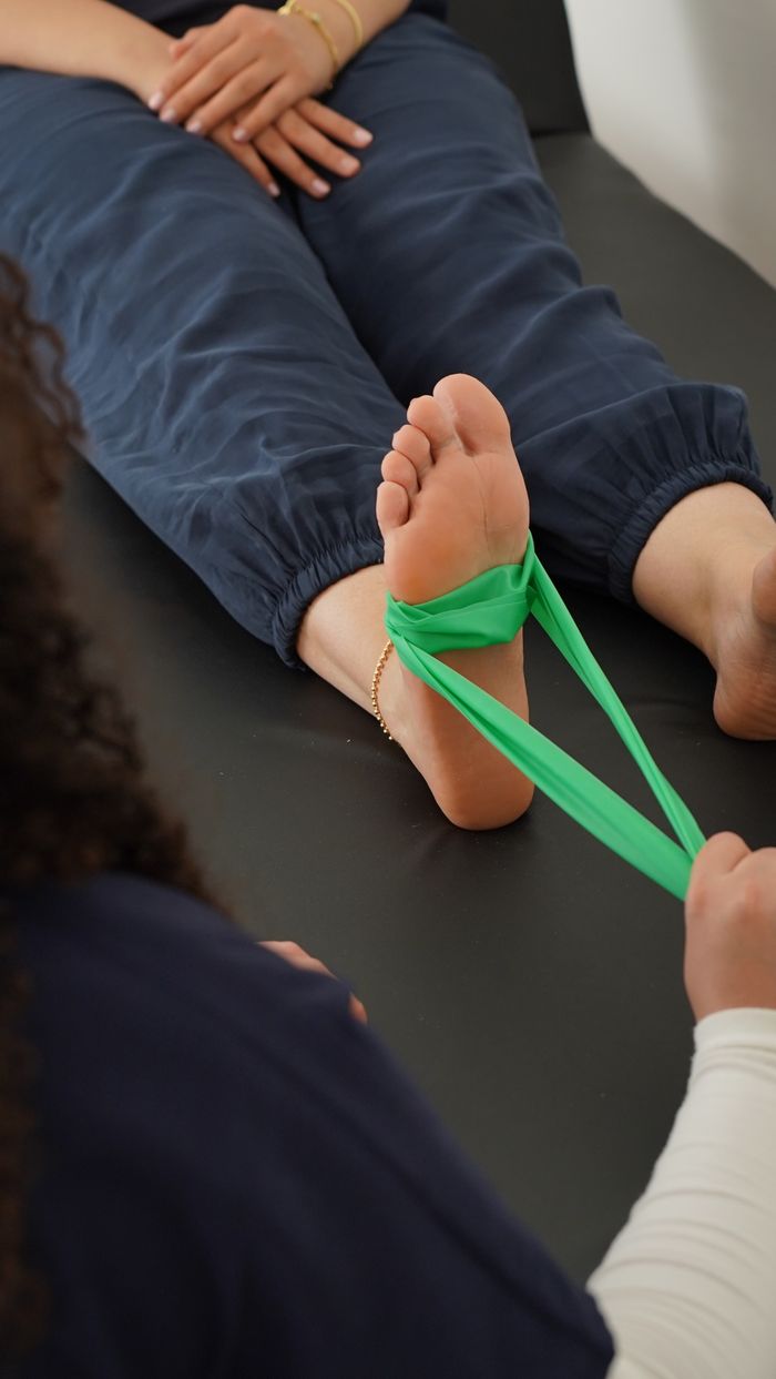 Close-up of a physical therapy session using a resistance band for foot rehabilitation.