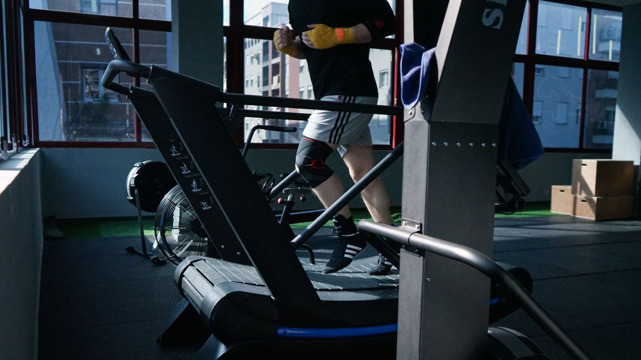 About Adult man exercising on a treadmill in a modern indoor gym setting.