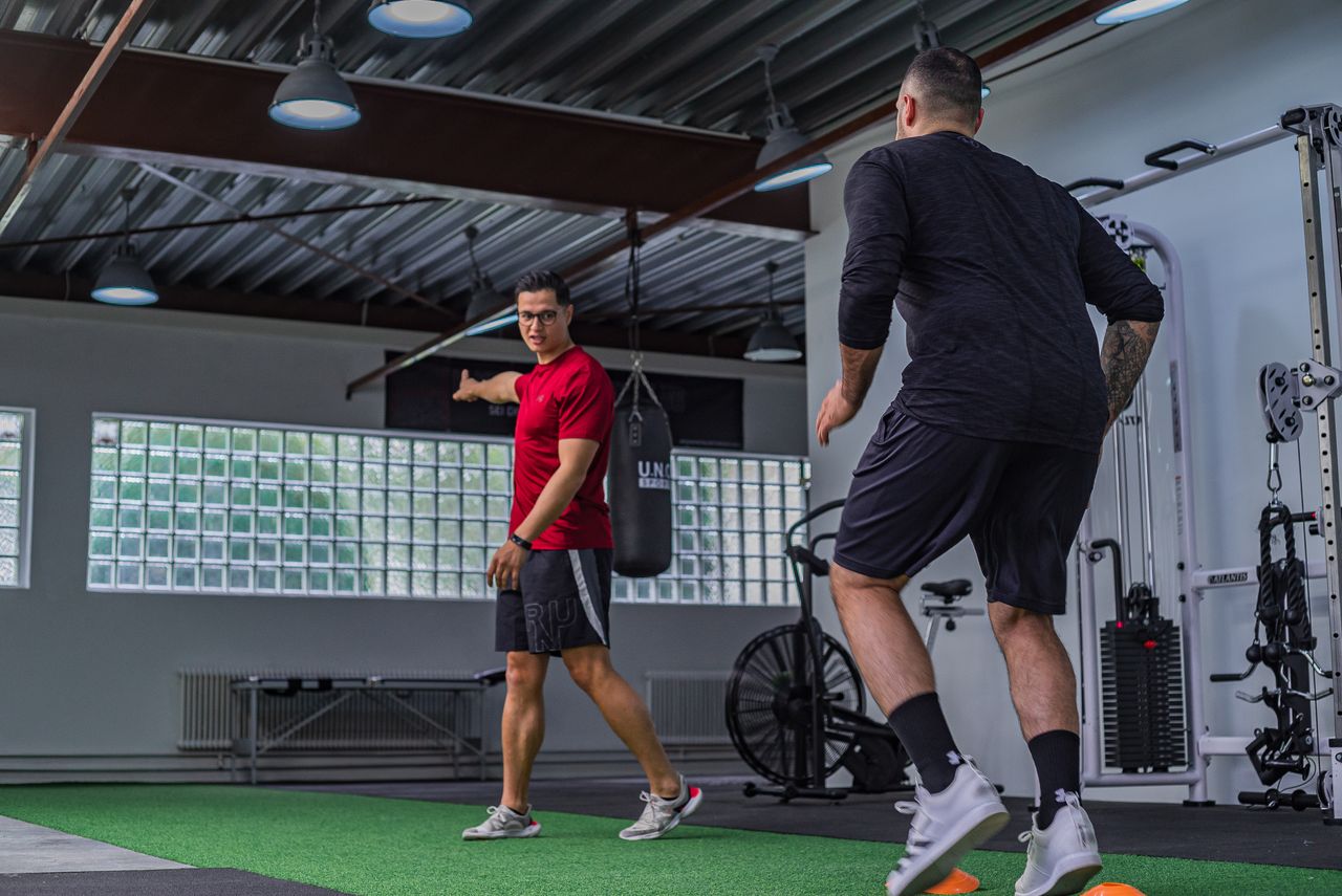 About Full body of muscular sportsman in activewear doing exercises with instructor in modern gym